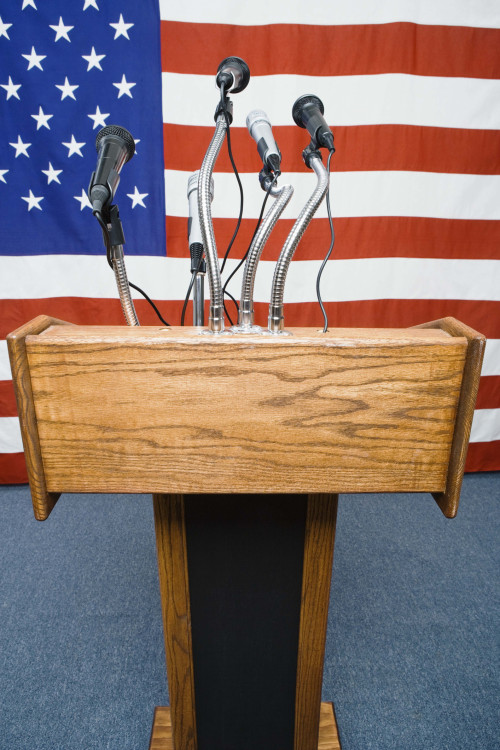 Podium with microphones by American flag Church Executive